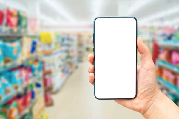 Mock up image of A hand holding a blank screen of smartphone on  a supermarket blurred background. Shopping online concept.