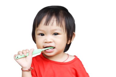 1-2 yaşlarındaki bir bebeğin portresi. Mutlu Asyalı kız çocuğu dişlerini fırçalama alıştırması yapıyor. Beyaz bir arka planda. Kırmızı pijama giyiyor. Sağlıklı ve çocuk kavramı.