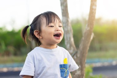 2 yaşındaki bir bebeğin portresi. Mutlu Asyalı kız çocuğu eğlendiğinde büyük bir kahkaha alır. Anın tadını çıkar. Bahçe parkında. Çocuk konsepti duyguları. 