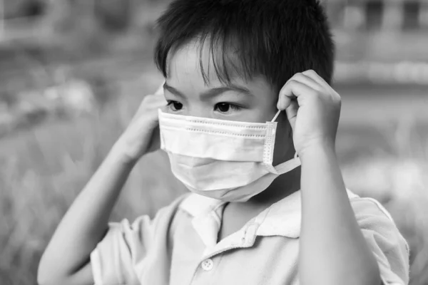 6 years old of Asian child boy wearing a protection mask for prevent Covid-19 ,Corona virus and PM 2.5 air pollution. He have an illness, Sore throat and flu. On white background. Healthy care.