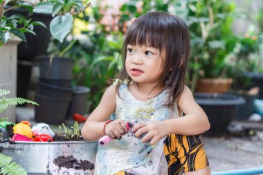 2 yaşındaki bir bebeğin portresi. Mutlu Asyalı kız çocuğu gülümsüyor ve kumaş maske takıyor çocuk parkında sürgülü bar oyuncağıyla oynuyor, sosyal mesafe öğreniyor ve çocuk konseptini aktif hale getiriyor..
