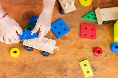 Tahta blok oyuncaklarıyla oynayan erkek ya da kız çocuğunun en iyi görüntüsü. Ahşap zeminde. 1-2 yaşlarında bir çocuk. Çocuk kavramının öğrenilmesi ve geliştirilmesi.