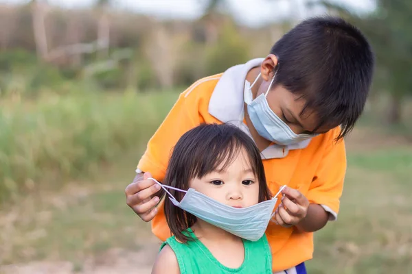 Yumuşak Odaklanma Küçük Kız Kardeşi Için Tıbbi Maske Takan Asyalı — Stok fotoğraf
