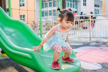 Portrait image of 2 yeas old baby. Happy Asian child girl smiling and laughing. She playing with slider bar toy at the playground. Learning and active of kids concept. clipart