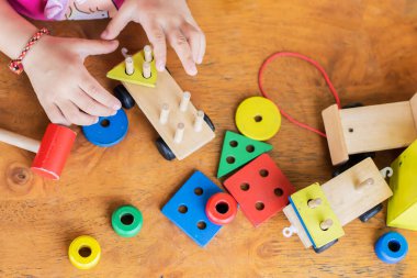 Tahta blok oyuncaklarıyla oynayan erkek ya da kız çocuğunun en iyi görüntüsü. Ahşap zeminde. 2 yaşında bir çocuk. Çocuk kavramının öğrenilmesi ve geliştirilmesi.