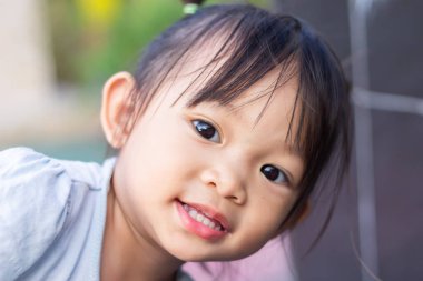 2-3 yaşlarındaki bir bebeğin portresi. Mutlu Asyalı kız çocuğu gülümsüyor ve kumaş maske takıyor. Çocuk parkında oynuyor. Sosyal uzaklık. Çocuk konseptini öğrenmek ve aktif olmak.