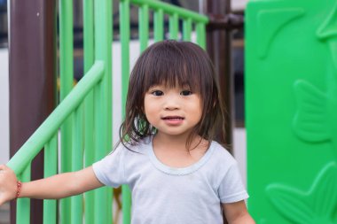 2-3 yaşlarındaki bir bebeğin portresi. Bahçedeki parkta gülümseyen ve rahatlatan mutlu Asyalı kız çocuğu. Beyaz gömlek giyen güzel bir kız. Yaz sezonu. Çocuklar ve sağlıklı konsept.