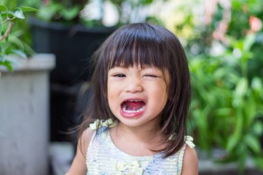 2-3 yaşlarındaki bir bebeğin portresi. Bahçedeki parkta gülümseyen ve rahatlatan mutlu Asyalı kız çocuğu. Beyaz gömlek giyen güzel bir kız. Yaz sezonu. Çocuklar ve sağlıklı konsept.