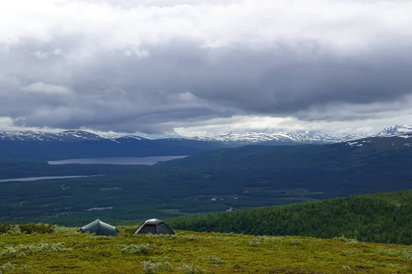 İsveç yürüyüş patikasındaki çadırlar. Dağların manzarası, bulutlar ve kar.