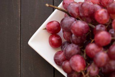 koyu ahşap zemin üzerinde kırmızı üzüm