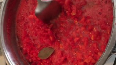 Çelik tencerede sıcak domates sosu kış için konserve yapıyor.