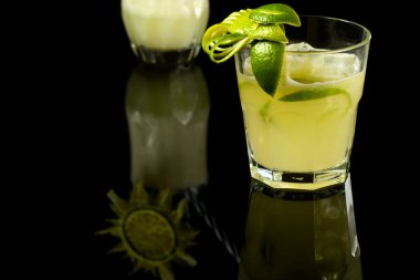 LEMON 'UN CAIPIRINHA TİPTİK BRAZİLYA BÜYÜK SÜRÜNÜ, karanlık bir masa üzerinde fotografı çekilmiştir