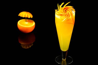 Siyah arka planda çekilmiş portakallı portakallı portakal suyu.