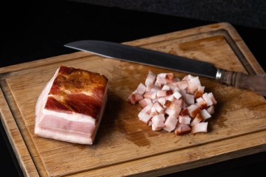 Siyah cam bir masanın üzerinde füme domuz pastırması.