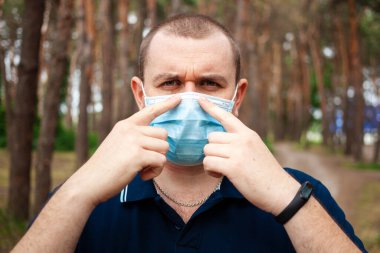 Sağlık, güvenlik ve salgın konsepti. Ormandaki diğer hastalıklardan korunmak için koruyucu maske takan genç adamın portresini kapat..