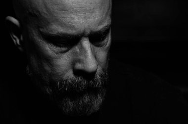 Gri sakallı yaşlı bir adamın siyah beyaz fotoğrafı.