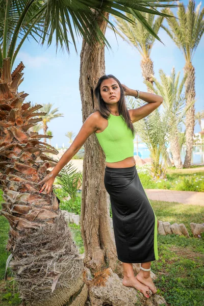 Girl sports appearance in brightly light green top and black skirt.