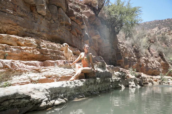 水着姿の少女が川沿いの崖の上に腰を下ろしている パラダイスバレー Agadir Morocco — ストック写真