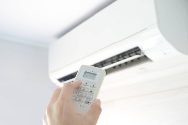 Adamın eli uzaktan kumanda ile açılıyor klima yatak odasında 25 santigrat dereceye kadar soğutuluyor. Sağlık kavramları ve enerji tasarrufları