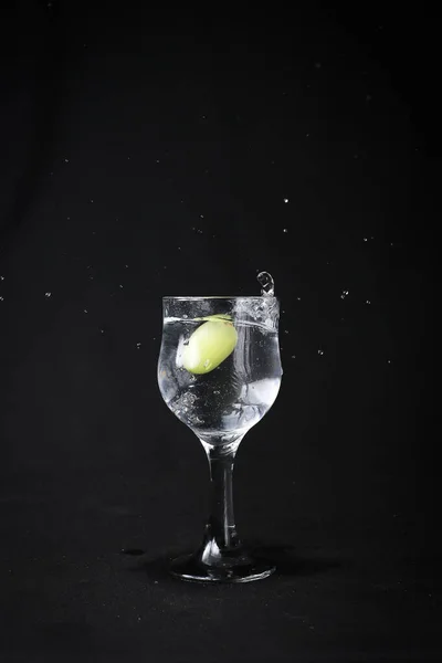 Víz Fröccsen Üvegből Fekete Alapon Zöld Szőlővel — Stock Fotó