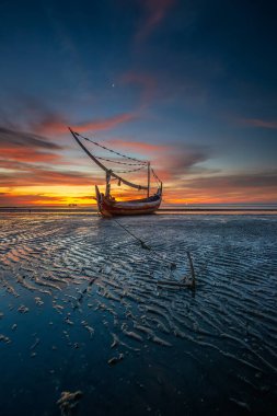 Endonezya geleneksel ahşap gemiler ve güzel kumsallar. Geleneksel Sasaknese teknesi Jukung Mlandingan sahilinde, Situbondo. Gün batımında sahilde balıkçı teknesi.