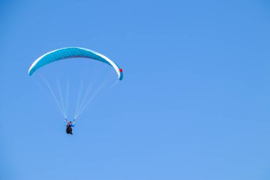 Mavi gökyüzünde süzülen paraglider.