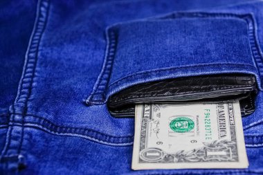 Siyah deri cüzdan, arkasında da kot pantolon ve kot pantolon var..