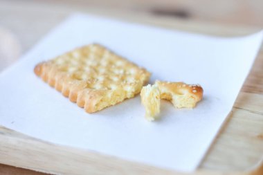 Kuru kraker kırıntısı. Tahta tabakta beyaz kağıt var..