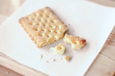 Kuru kraker kırıntısı. Tahta tabakta beyaz kağıt var..