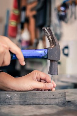 Kapalı çekiçle tahtaya çivi çakan işçi, klasik tarzda.