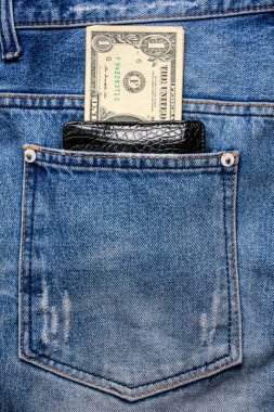 Siyah deri cüzdan, arkasında da kot pantolon ve kot pantolon var..