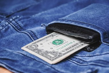 Siyah deri cüzdan, arkasında da kot pantolon ve kot pantolon var..