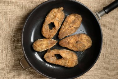 Tavada bir dilim lezzetli kızarmış balık, üst manzara, çuval bezi arka plan.