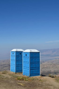 Dağlarda iki adet mavi portatif tuvalet, Özbekistan, turistler için dağın tepesinde. Beldersay.