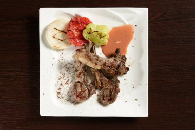 Ahşap bir masada ızgara domates, soğan ve dolmalık biberli ızgara sığır pirzolası. Üst Manzara. Restoran ve kafe menüleri için fotoğraflar