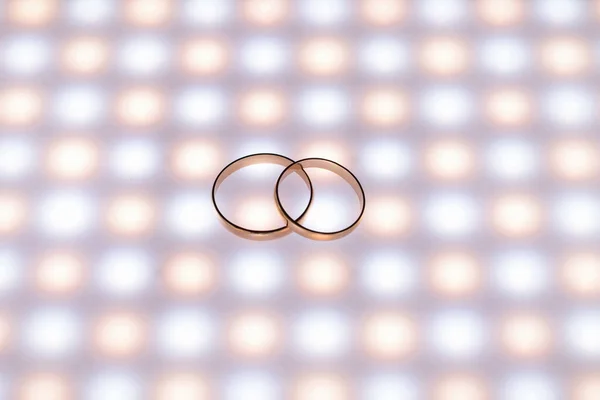 Wedding rings close-up, with LED lighting and dark background. View top