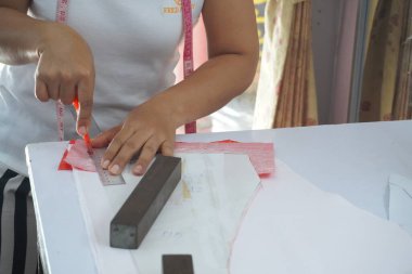 Asyalı kadın kağıt üzerine çiziyor, küçük işletme içeride.