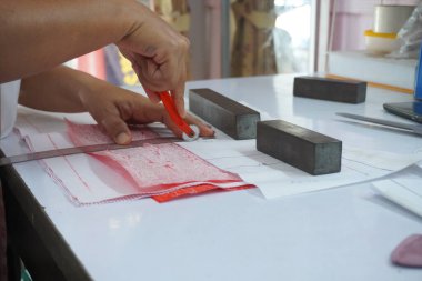 Asyalı kadın kağıt üzerine çiziyor, küçük işletme içeride.