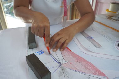 Asyalı kadın kağıt üzerine çiziyor, küçük işletme içeride.