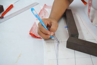 Asyalı kadın kağıt üzerine çiziyor, küçük işletme içeride.