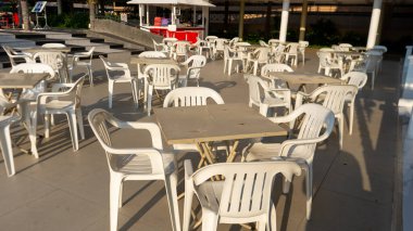 Geniş alanda bir sürü plastik sandalye var ama kimse üzerinde oturmuyor..