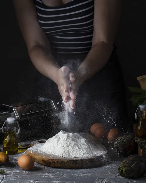 women's hands making pasta dark rustic style