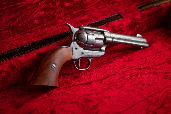 Old wild west revolver with brown wood grips over red velvet