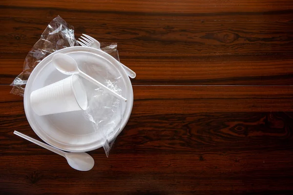 Some pieces of a disposable white plastic crockery in a wooden table