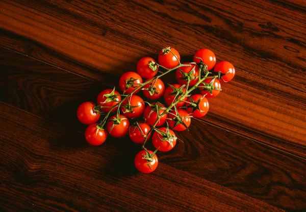 Red cherry tomatoes over a dark brown wooden table