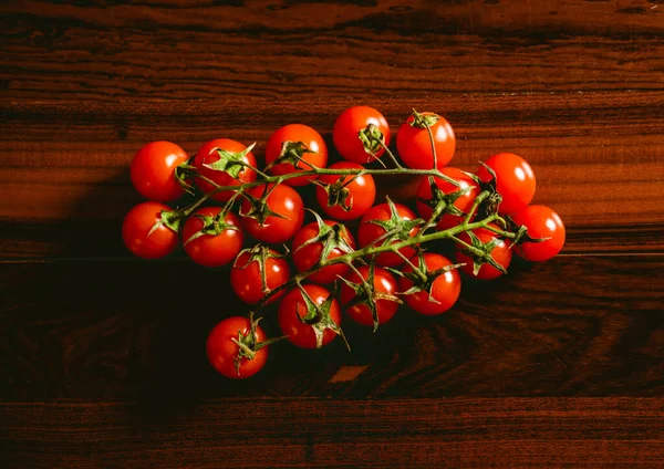 Red cherry tomatoes over a dark brown wooden table