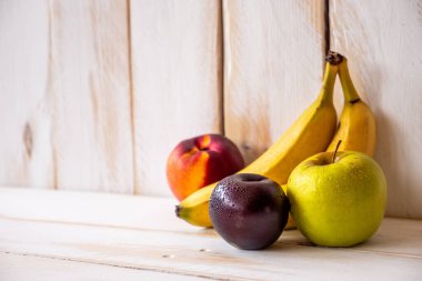 Taze meyvelerden oluşan küçük bir grup ve kopyalama alanı olan beyaz ahşap duvar..