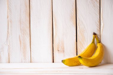 İki sarı muzlu beyaz ahşap duvar ve kopyalama alanı.