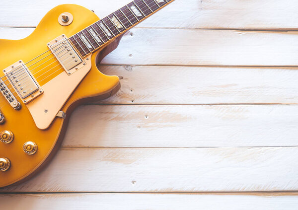 Beautiful classic golden electric guitar on a white wooden table, with copy space.