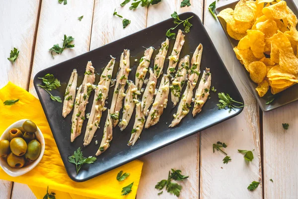 三道菜 马铃薯片 采摘的凤尾鱼和绿色橄榄在一个白色的木制桌子上与欧芹叶 在酒吧里吃的典型西班牙小吃 — 图库照片